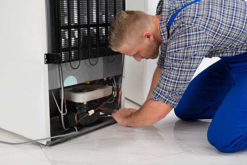 Appliance Repair Tech Working On Fridge Mod